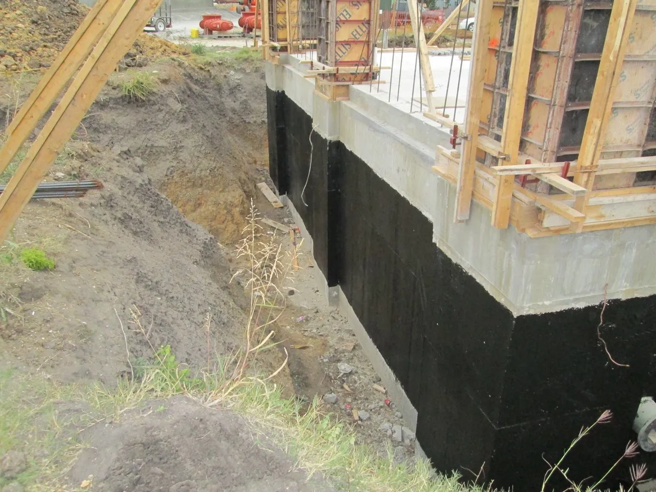 A close up of the foundation wall with black waterproofing.