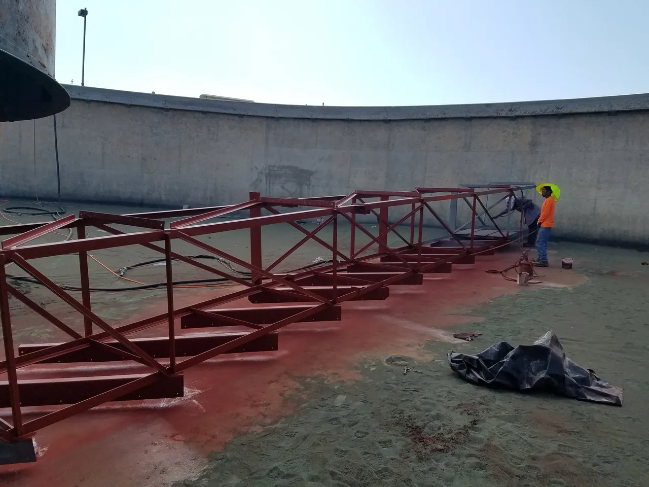 A man standing next to a red metal structure.