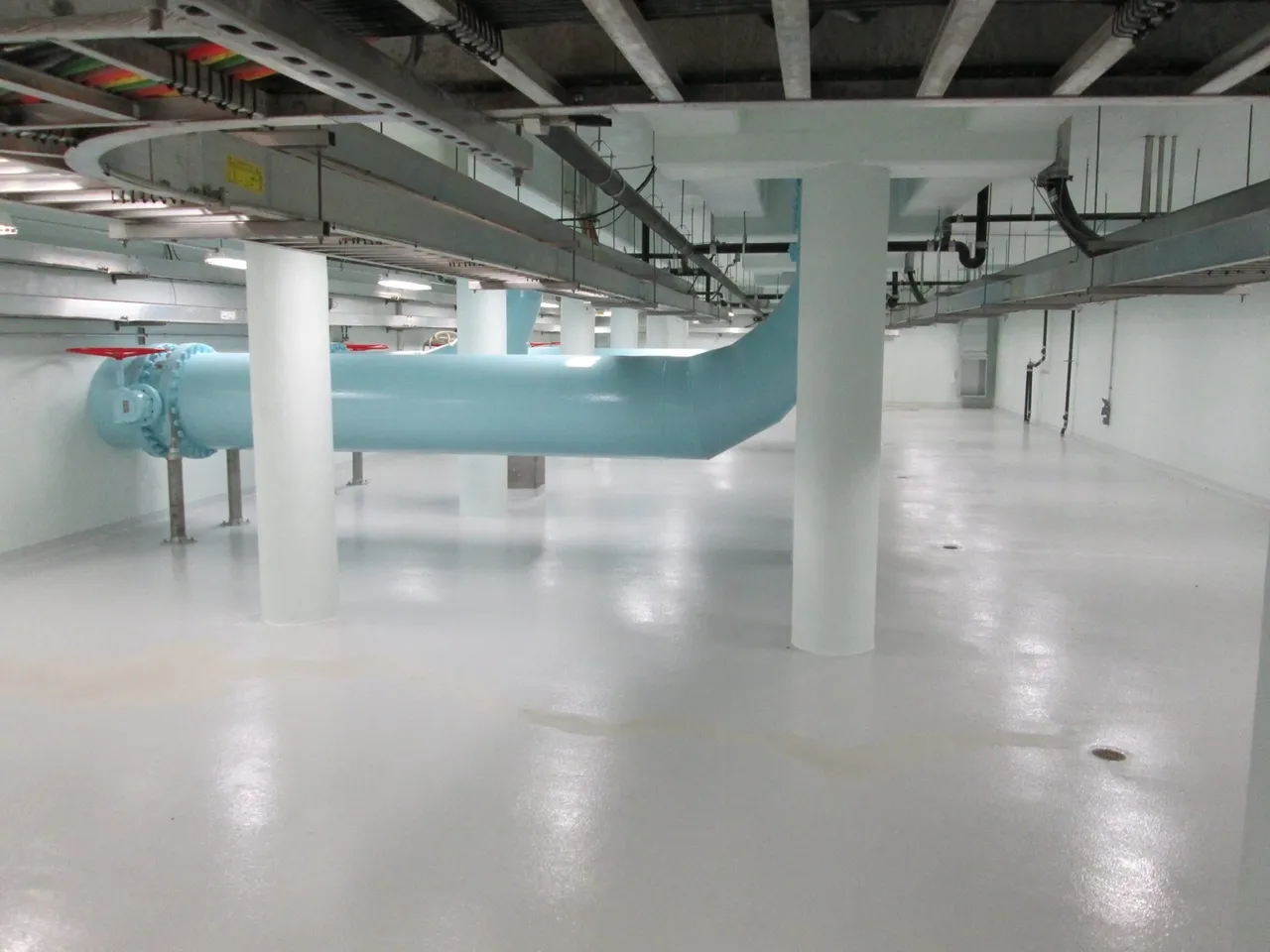 A large room with white floors and blue pipes.
