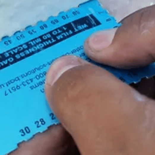A person holding onto the bottom of a ticket.